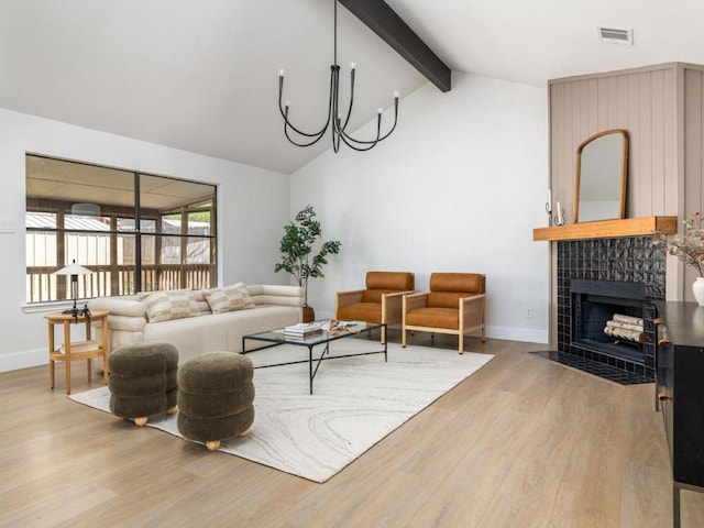 living room featuring light wood-style flooring, visible vents, baseboards, a fireplace, and beam ceiling