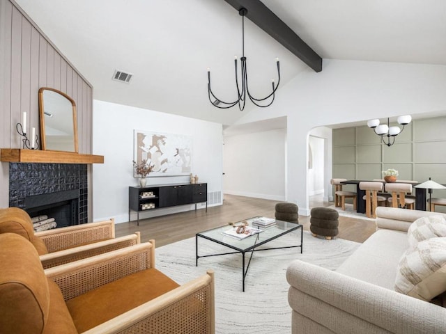living room with a notable chandelier, lofted ceiling with beams, wood finished floors, visible vents, and arched walkways