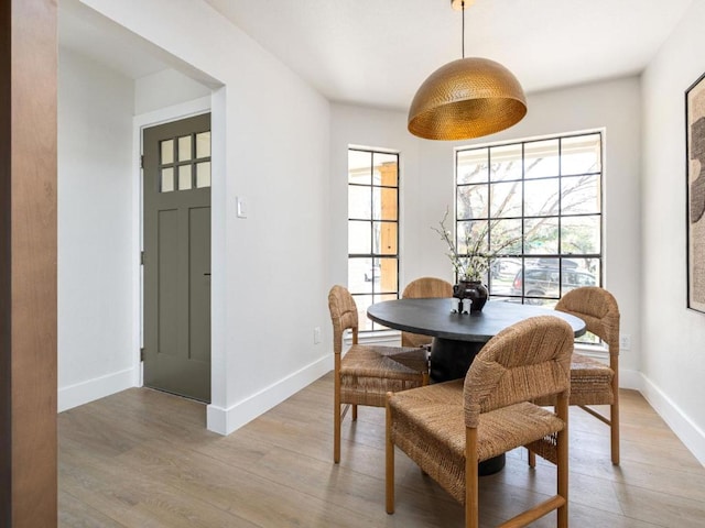 dining area with baseboards and light wood finished floors