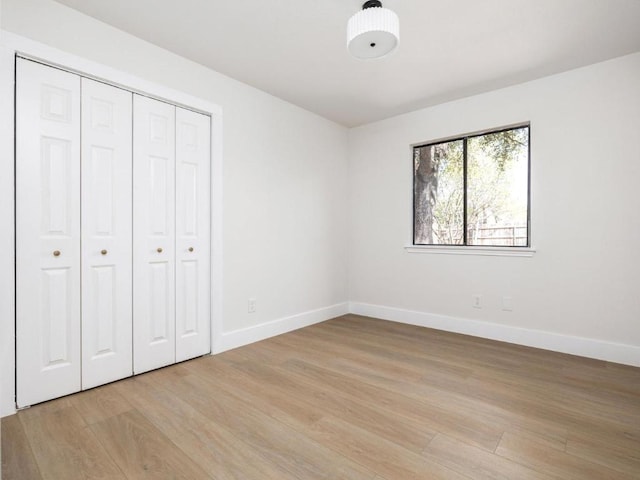 unfurnished bedroom with baseboards, a closet, and light wood finished floors