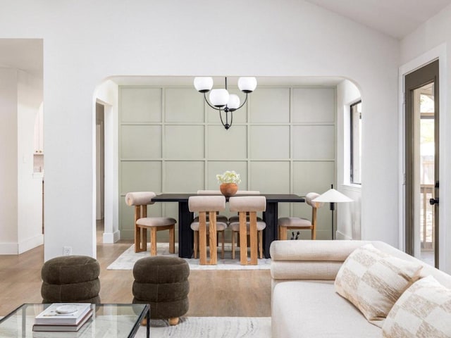 living room with baseboards, lofted ceiling, wood finished floors, and arched walkways