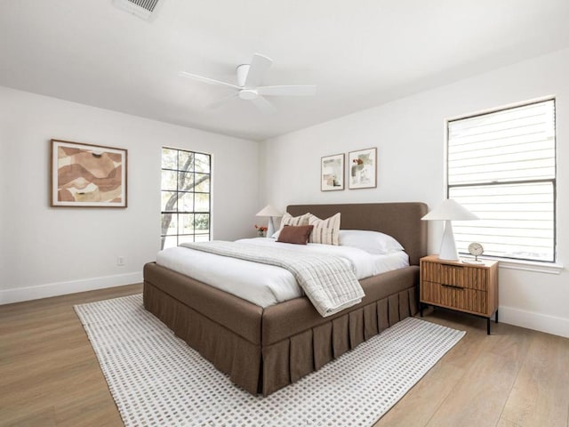 bedroom with a ceiling fan, baseboards, light wood finished floors, and visible vents
