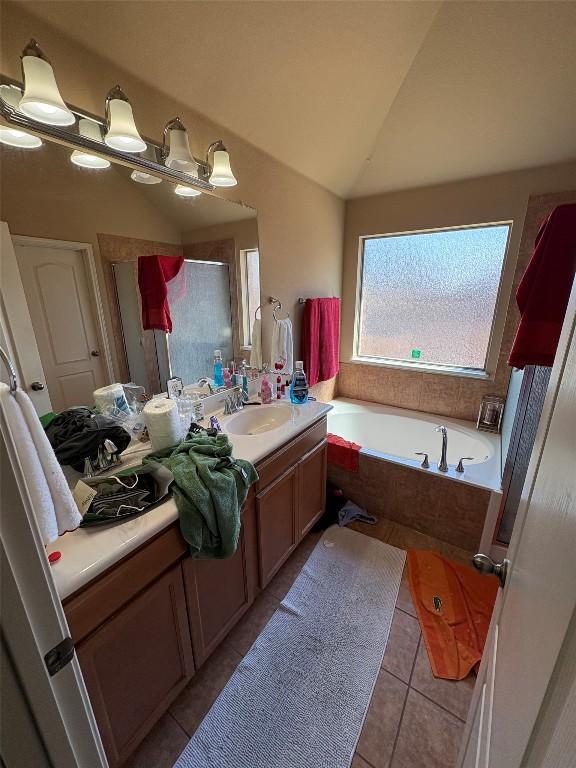 2316 Dovetail St, Pflugerville, TX 78660 - bathroom with tile patterned flooring, a garden tub, vanity, vaulted ceiling, and a shower with door