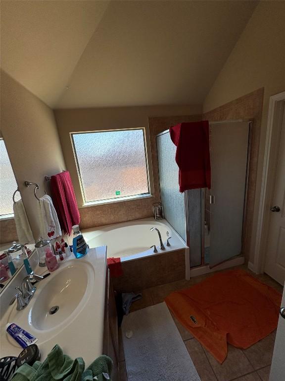 2316 Dovetail St, Pflugerville, TX 78660 - full bathroom featuring lofted ceiling, a shower stall, a garden tub, vanity, and tile patterned flooring