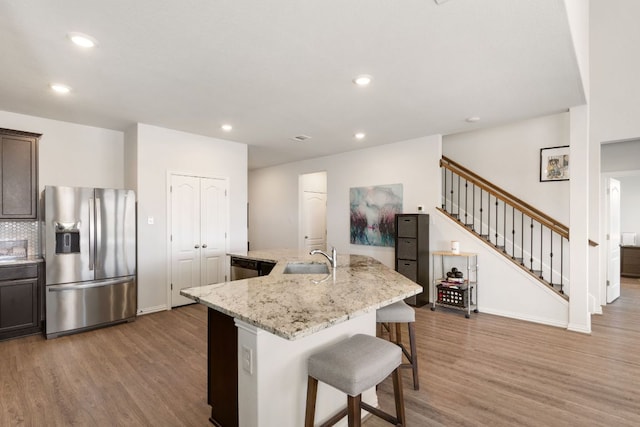 277 Biscayne Bay Bnd, Kyle, TX 78640 - kitchen with stainless steel fridge, wood finished floors, a kitchen bar, an island with sink, and recessed lighting