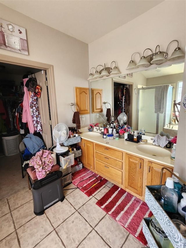 full bath featuring double vanity, a walk in closet, a stall shower, a sink, and tile patterned floors
