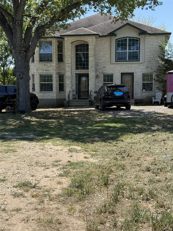 view of front of property featuring a front lawn and stone siding
