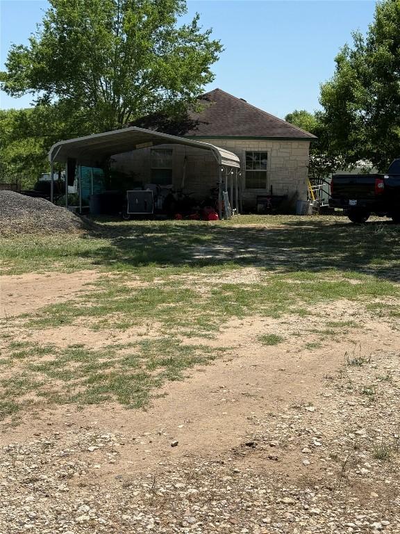 view of side of home with dirt driveway and a carport