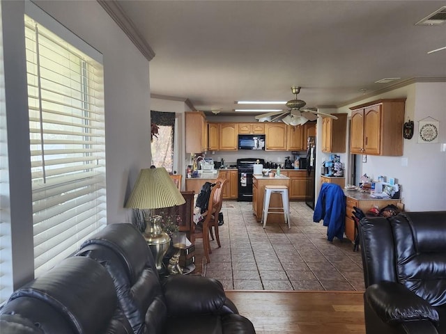 living area with ceiling fan, visible vents, ornamental molding, and wood finished floors
