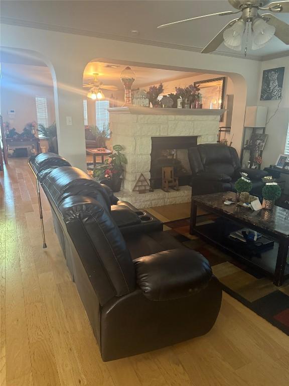 living area with light wood-type flooring, arched walkways, and ceiling fan