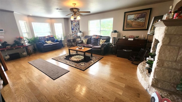 1149 State Highway 21 W Unit A, Cedar Creek, TX 78612 - living area featuring crown molding, ceiling fan, wood finished floors, healthy amount of natural light, and a stone fireplace