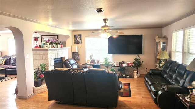 1149 State Highway 21 W Unit A, Cedar Creek, TX 78612 - living room featuring a ceiling fan, ornamental molding, light wood-style flooring, a fireplace, and arched walkways