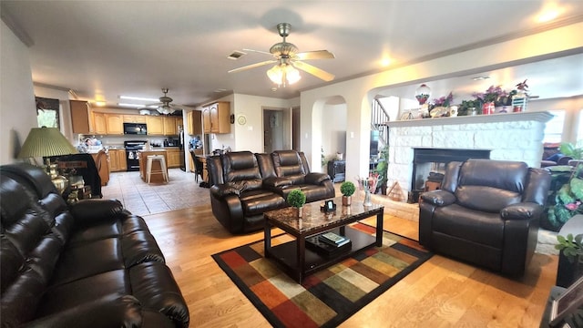1149 State Highway 21 W Unit A, Cedar Creek, TX 78612 - living area with ceiling fan, light wood-style flooring, arched walkways, and a fireplace