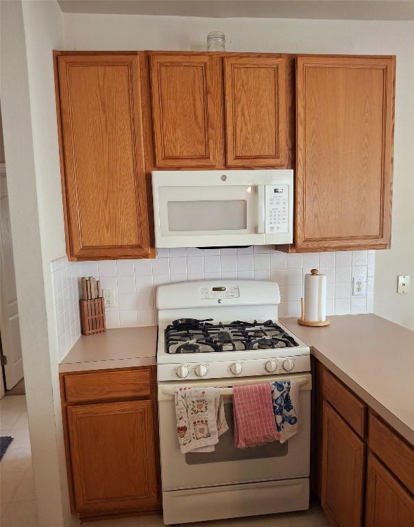 1709 Camas Dr, Austin, TX 78728 - kitchen with white appliances, tasteful backsplash, light countertops, and brown cabinetry