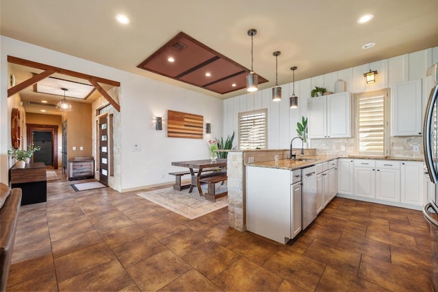 kitchen featuring a peninsula, a sink, stainless steel appliances, white cabinets, and light stone countertops