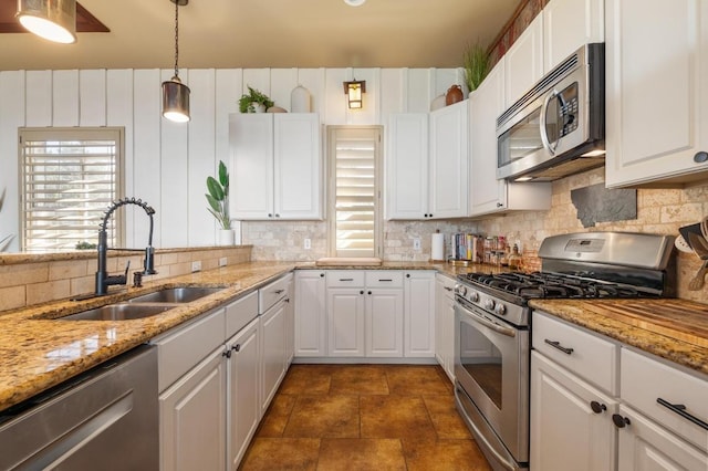 kitchen featuring backsplash, a wealth of natural light, appliances with stainless steel finishes, and a sink