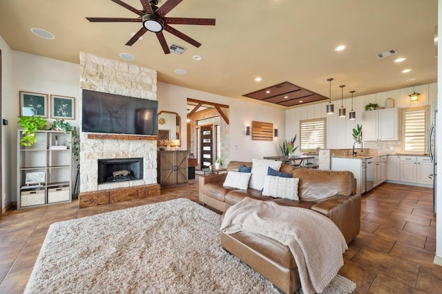 living area featuring a fireplace, a ceiling fan, visible vents, and recessed lighting