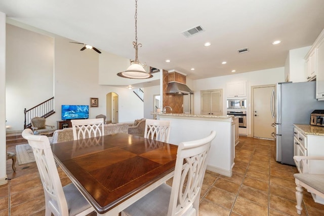 12029 Portobella Dr, Austin, TX 78732 - dining space featuring arched walkways, stairs, ceiling fan, recessed lighting, and light tile patterned floors