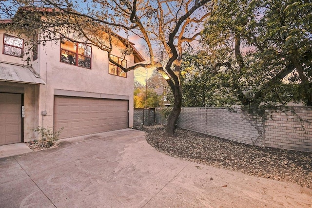 1701 Ravey St, Austin, TX 78704 - view of side of home with stucco siding, an attached garage, and driveway