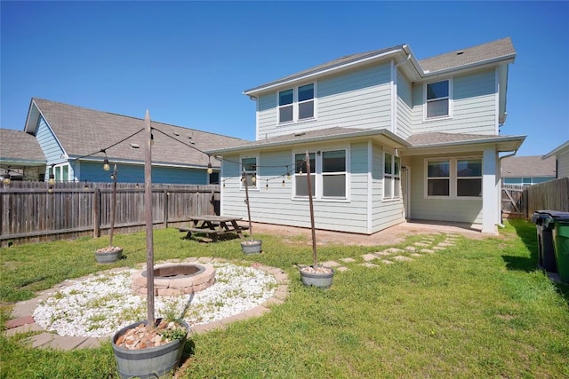 back of house with a fenced backyard, a fire pit, and a lawn
