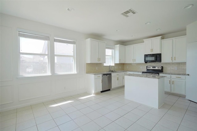 kitchen featuring white cabinets, visible vents, decorative backsplash, stainless steel appliances, and a sink