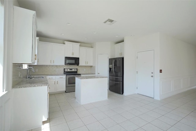 kitchen with visible vents, light tile patterned floors, a sink, black appliances, and decorative backsplash