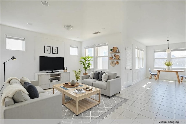 living area featuring light tile patterned floors, visible vents, and baseboards