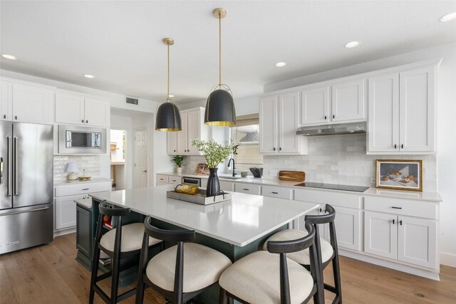 9943 Derecho Dr, Austin, TX 78737 - kitchen with stainless steel appliances, backsplash, light countertops, a breakfast bar area, and a kitchen island