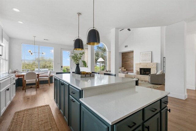 9943 Derecho Dr, Austin, TX 78737 - kitchen with light wood-type flooring, a center island, light countertops, recessed lighting, and a fireplace