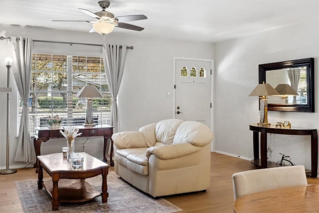 living area with wood finished floors, baseboards, and ceiling fan