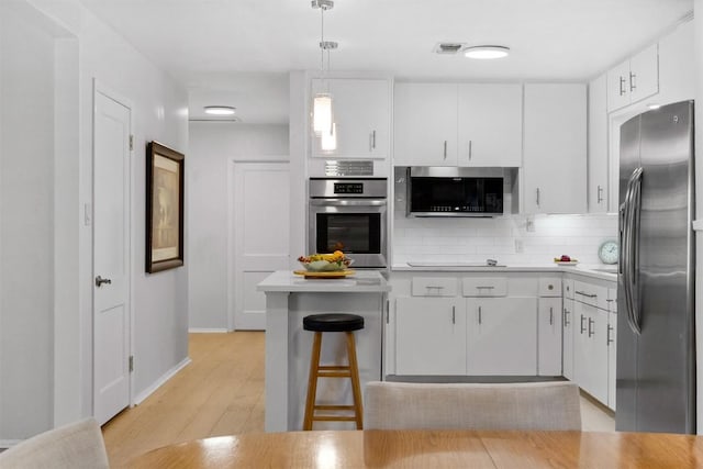 kitchen with decorative backsplash, stainless steel appliances, light wood finished floors, light countertops, and white cabinetry