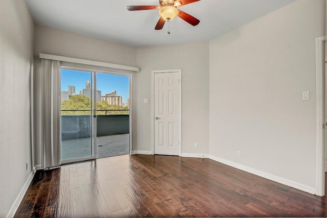 empty room with dark wood finished floors, ceiling fan, and baseboards