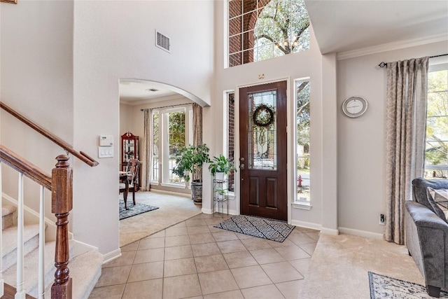 entrance foyer featuring stairs, light colored carpet, ornamental molding, and visible vents