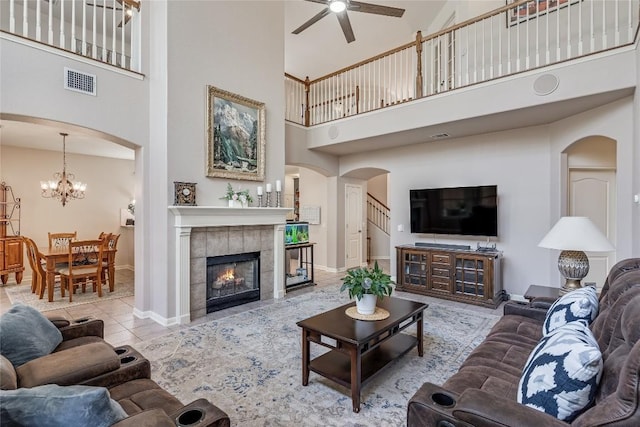 2535 Crenshaw Dr, Round Rock, TX 78664 - tiled living area featuring a high ceiling, ceiling fan, arched walkways, baseboards, and a fireplace