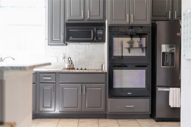 2535 Crenshaw Dr, Round Rock, TX 78664 - kitchen with black appliances, gray cabinetry, decorative backsplash, light tile patterned flooring, and light stone countertops