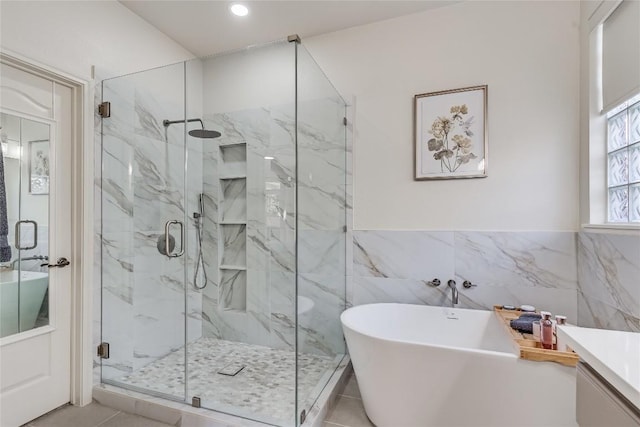 2535 Crenshaw Dr, Round Rock, TX 78664 - bathroom featuring a freestanding bath, a marble finish shower, vanity, tile walls, and wainscoting