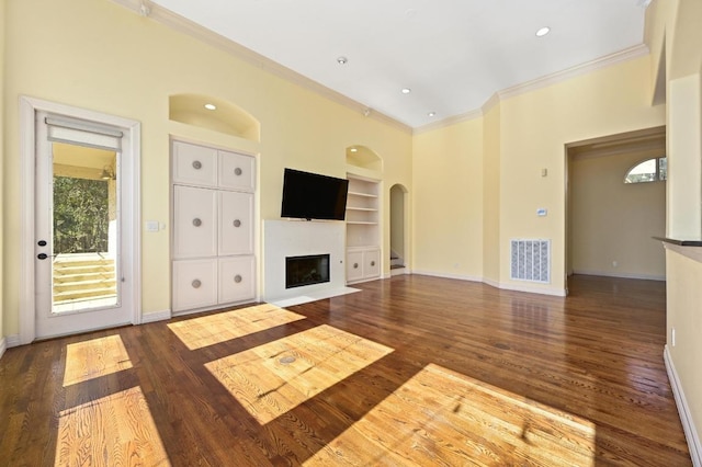 5903 Cane Pace, Austin, TX 78746 - unfurnished living room with arched walkways, crown molding, built in features, a glass covered fireplace, and baseboards