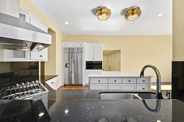 5903 Cane Pace, Austin, TX 78746 - kitchen featuring appliances with stainless steel finishes, wall chimney exhaust hood, a sink, decorative backsplash, and white cabinetry