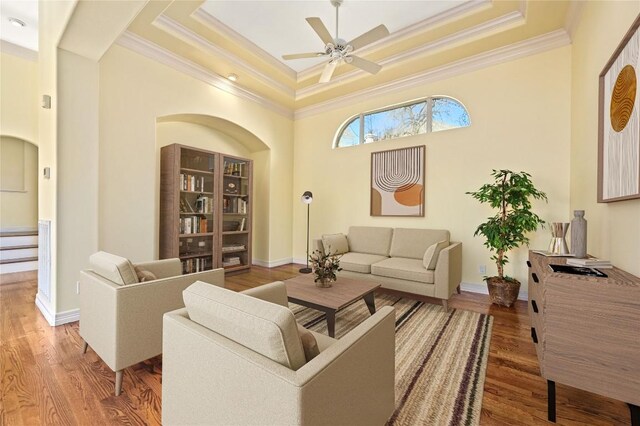 living room featuring a tray ceiling, ceiling fan, and ornamental molding