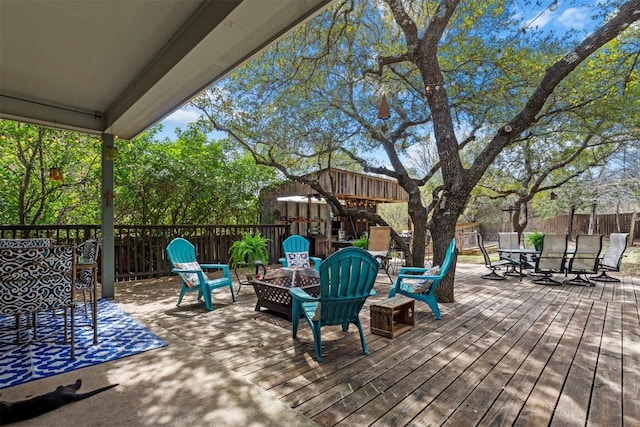 wooden deck with outdoor dining area, a fire pit, and fence