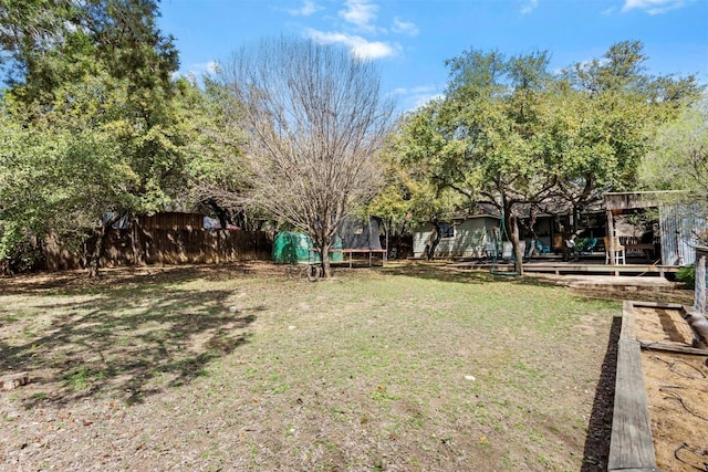 view of yard featuring fence, a trampoline, and a wooden deck