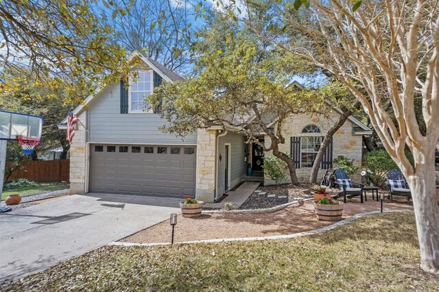 view of front facade featuring an attached garage, fence, stone siding, and concrete driveway