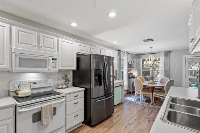 kitchen featuring a chandelier, white cabinetry, white appliances, and visible vents