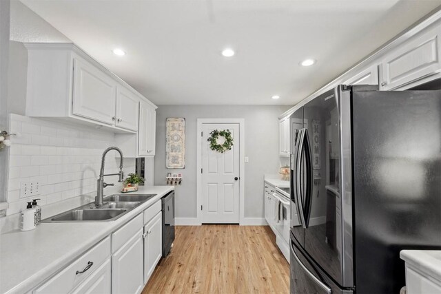 kitchen with a sink, light countertops, white cabinets, and freestanding refrigerator