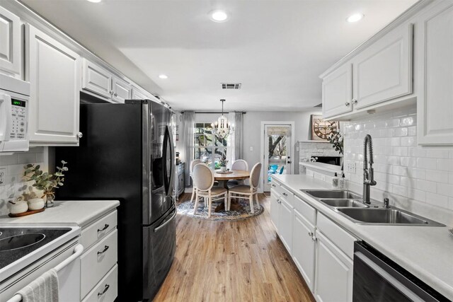 kitchen with visible vents, a sink, a stone fireplace, white appliances, and backsplash