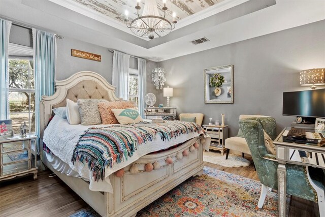 bedroom with a notable chandelier, visible vents, a tray ceiling, multiple windows, and wood finished floors