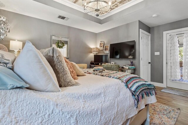 bedroom featuring visible vents, baseboards, ornamental molding, a chandelier, and wood finished floors