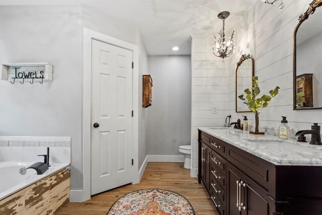 bathroom featuring a sink, toilet, a notable chandelier, and a bath