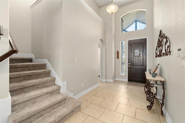 100 Adorno Ln, Georgetown, TX 78628 - foyer entrance featuring arched walkways, stairs, a high ceiling, light tile patterned floors, and baseboards