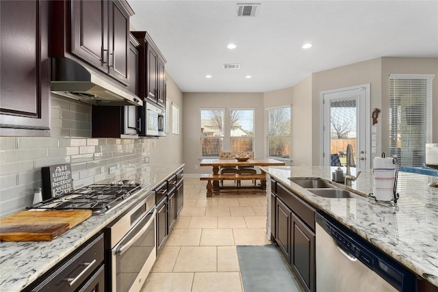 100 Adorno Ln, Georgetown, TX 78628 - kitchen with a sink, stainless steel appliances, under cabinet range hood, decorative backsplash, and recessed lighting
